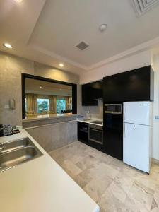 a kitchen with a white refrigerator and a sink at منتجع موفون بيتش in Al Khobar