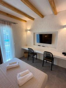 a bedroom with a bed and two chairs and a tv at Golden Star in Ios Chora