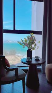 a room with a table and a vase with a plant at APEC Mandala Mũi Né Official - Diễm Phạm Travel in Phan Thiet