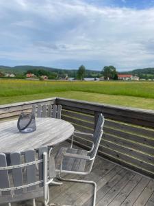 Ein Tisch und Stühle auf einer Terrasse mit Blick auf ein Feld in der Unterkunft Låbbyn15 in Årjäng