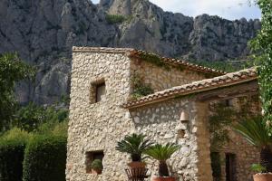 a stone building with plants in front of a mountain at Torre de Arriba Casa Rural in Benimantell +35 photos