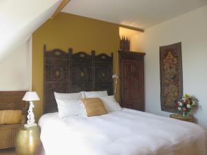 a bedroom with a large white bed with a wooden headboard at Chambres d'Hôtes L’Échappée Belle in Saint-Brisson-sur-Loire