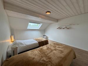 a bedroom with two beds and a ceiling with a window at Chez Marraine in Nassogne
