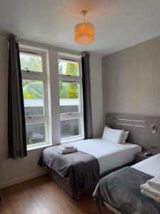 a bedroom with two beds and two windows at OX Hotel Spean Bridge in Spean Bridge