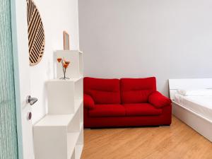 a red couch in a room with a bed at Da Nonno Eddie - tranquillo bilocale - wi-fi - tv - parcheggio vicino in Trieste