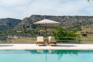 two chairs and an umbrella next to a swimming pool at Tenuta Madre Vita in Syracuse