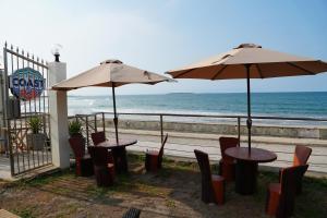 two tables and chairs with umbrellas on the beach at The Coast By RAD in Talisay