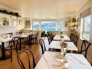 a restaurant with tables and chairs with mountains in the background at Ardvreck House in Ullapool