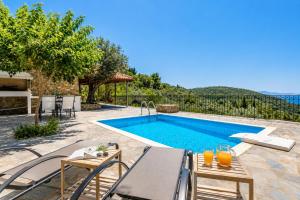 a villa with a swimming pool with a table and chairs at Oak Tree Cottage in Pefkias +9 photos