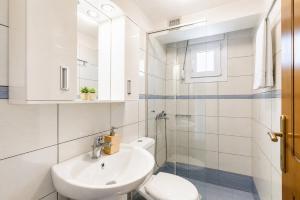 a white bathroom with a toilet and a sink at Oak Tree Cottage in Pefkias