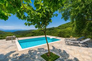 a swimming pool with a tree in a yard at Oak Tree Cottage in Pefkias