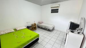 a bedroom with a green bed and a refrigerator at Pousada Zambaiam in Torto