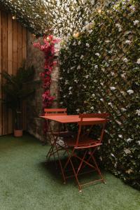 a red chair sitting next to a hedge with flowers at La Pimenta - SPA privatif & expérience immersive in Dole