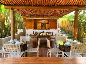 a patio with tables and chairs under a pergola at Pousada Awêry Caraíva in Caraíva