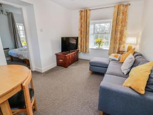 a living room with a blue couch and a tv at The Old Coach House in Lockerbie