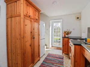 a kitchen with wooden cabinets and a white refrigerator at The Old Coach House in Lockerbie