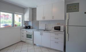 a kitchen with white cabinets and a sink and a refrigerator at Big Blue Pefkohori in Pefkochori