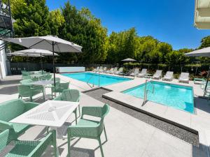 a swimming pool with tables and chairs next to a swimming pool at Pater Apartments and Rooms in Siófok