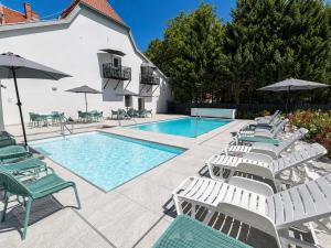 a pool with chaise lounge chairs and umbrellas at Pater Apartments and Rooms in Siófok