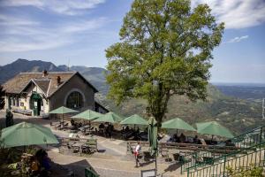 a restaurant with tables and green umbrellas and a building at Hôtel du Clos Fleuri in Lourdes