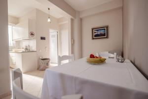 a white kitchen with a table with a bowl of fruit on it at Elidon Apartments in Sarandë +184 photos