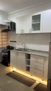 a kitchen with white cabinets and a sink and a stove at Olivewood Apartments in Ankuru