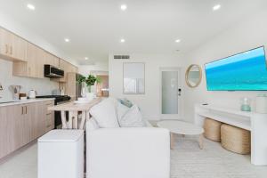 a white living room with a white couch and a kitchen at Casa Coral - Boca Poolside Escape in Boca Raton