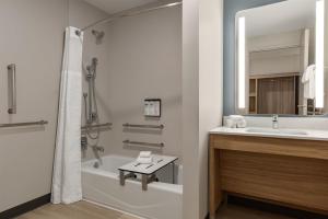 a bathroom with a tub and a sink and a mirror at Hyatt Studios Harrisonburg in Harrisonburg +38 photos