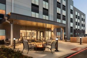 a patio with chairs and a fire pit in front of a building at Hyatt Studios Harrisonburg in Harrisonburg