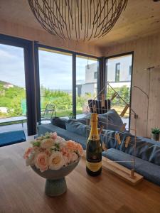 a bottle of champagne and a bowl of flowers on a table at Hillside Olive Apartmanház közös WELLNESsell in Pécs