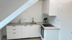a white kitchen with white cabinets and a sink at Atelier überm Hof in Alzenau
