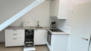 a kitchen with white cabinets and a dishwasher at Atelier überm Hof in Alzenau
