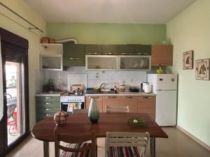 a kitchen with a table and a white refrigerator at Catherine Seaside Apartment in Ouranoupoli