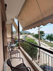 a balcony with tables and chairs and a view of the ocean at Catherine Seaside Apartment in Ouranoupoli