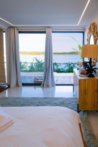 a bedroom with a bed and a large window at Koko Beach - Honeymoon Suite in Vila Praia Do Bilene