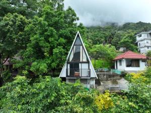 a small house with a triangular roof and a balcony at Mist Farm Resort in Avanāshi