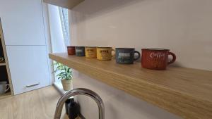 a row of coffee mugs sitting on a wooden shelf at Bytík Hlohovec Centrum in Hlohovec