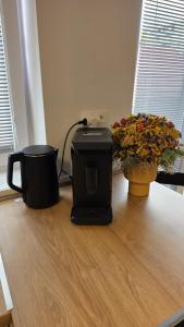 a coffee maker and two flowers on a wooden floor at Bytík Hlohovec Centrum in Hlohovec +8 photos