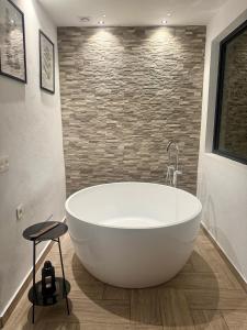 a white tub in a bathroom with a stone wall at CUEVAS del PEÑÓN in Grazalema