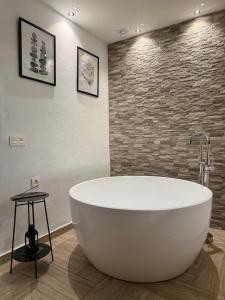 a large white tub in a bathroom with a brick wall at CUEVAS del PEÑÓN in Grazalema