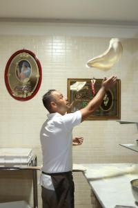 a man standing in a kitchen holding a piece of food at Hotel Il Quadrifoglio in Torre del Greco