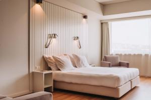 a hotel room with a bed and a chair at Hotel Flor De Sal by The Editory in Viana do Castelo +69 photos