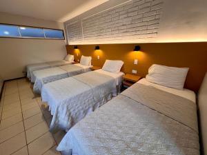 a hotel room with three beds in a room at Hotel Qamiri in Arica