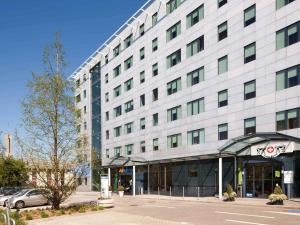 a large white building with a parking lot in front of it at Novotel Suites Genève Aéroport in Geneva