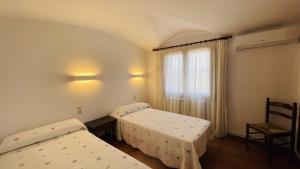a room with two beds and a chair and a window at Casa la Borna in Begur +21 photos