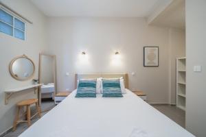 a bedroom with a large white bed and a mirror at Tassos Cottage Fiskardo in Fiskardo
