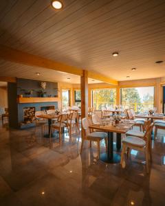 a restaurant with wooden tables and chairs and a fireplace at Tungulú - Hotel Boutique & Cabañas in Puerto Montt