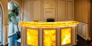 a hotel reception desk with yellow lights in a lobby at Hotel Begolli in Prishtinë