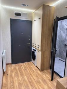 a laundry room with a black door and a washing machine at Fantastico 270 in Batumi