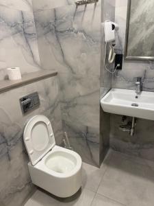 a bathroom with a white toilet and a sink at Fantastico 270 in Batumi +5 photos